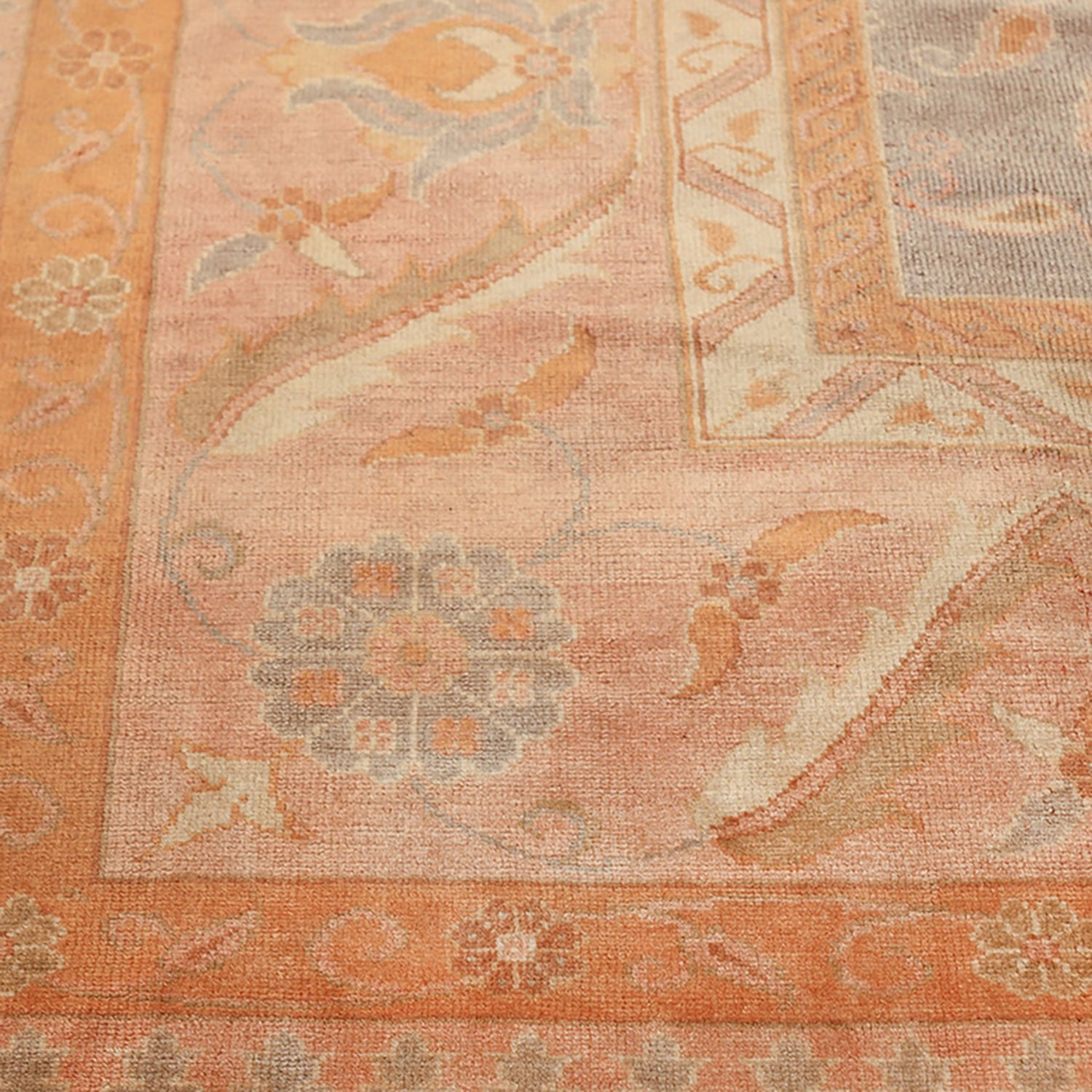 Intricate floral rug with warm, faded colors and symmetrical design.
