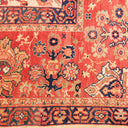 Intricate vintage Persian rug with rich red-orange hues and traditional motifs.