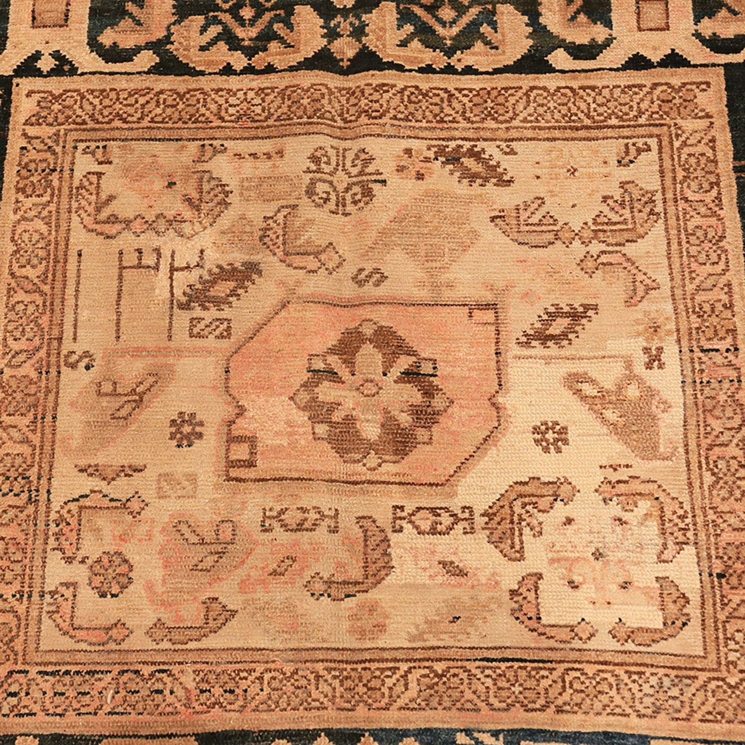 Close-up of an antique carpet with intricate patterns and muted colors.