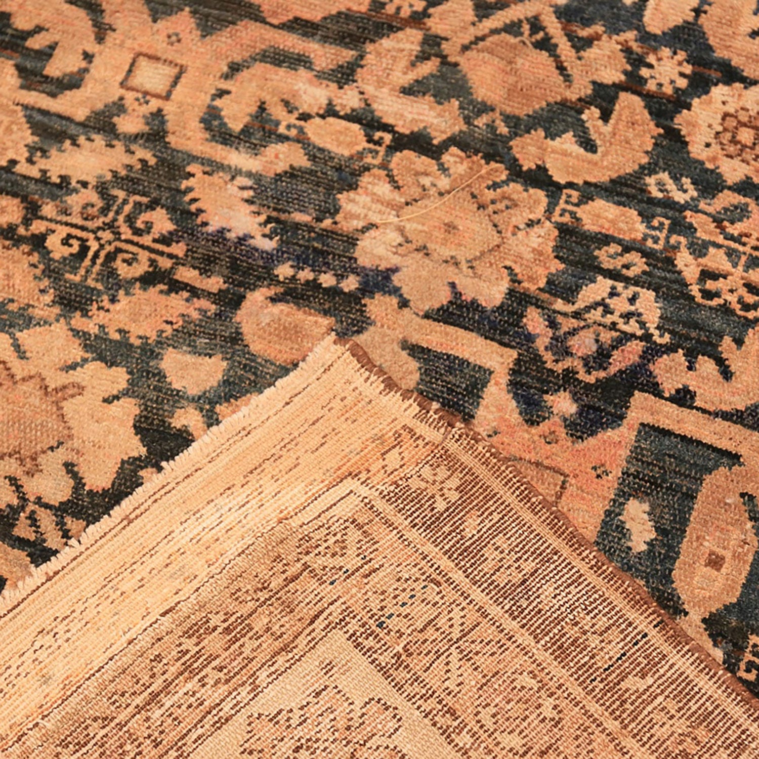 Intricate, traditional rug with floral motifs exhibits signs of age.