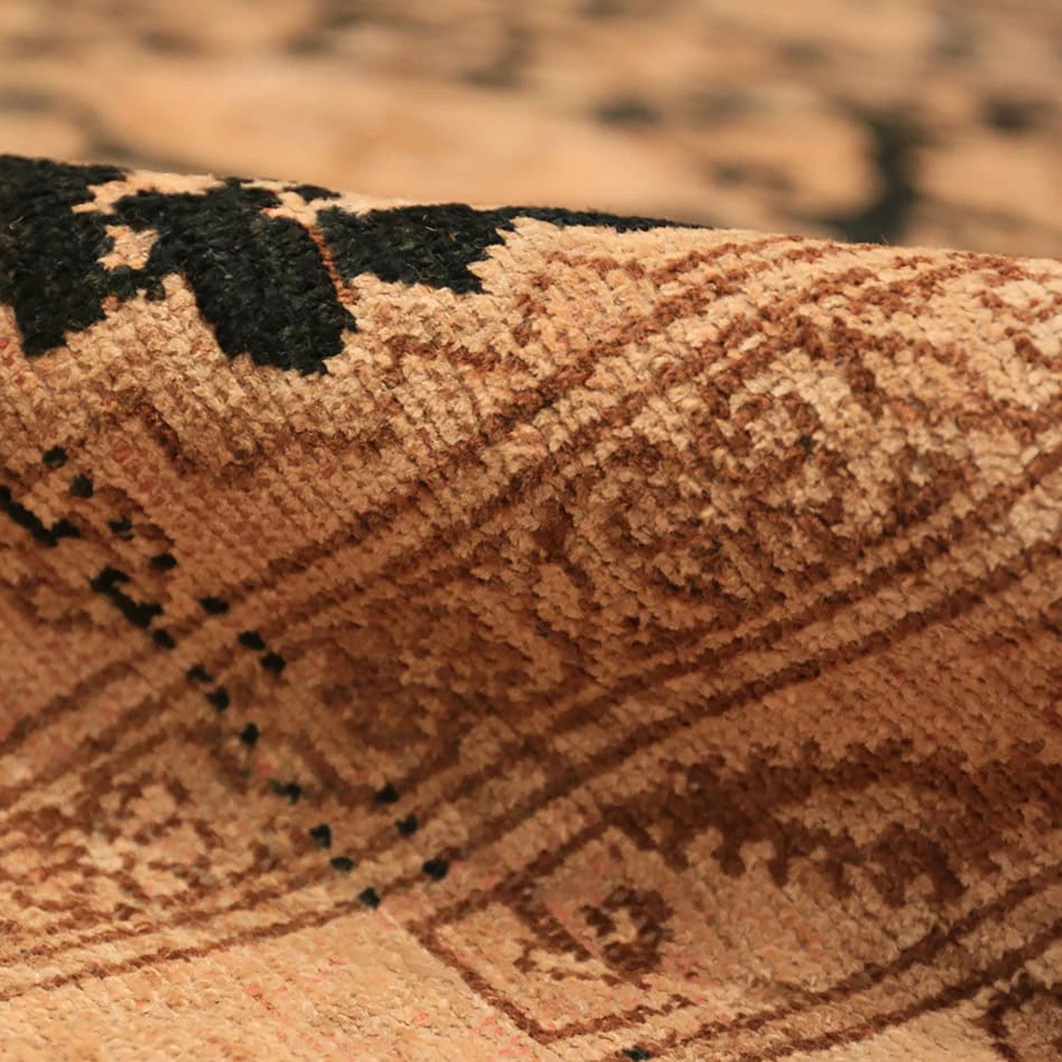 Close-up of rolled-up carpet revealing intricate pattern and dark accents.