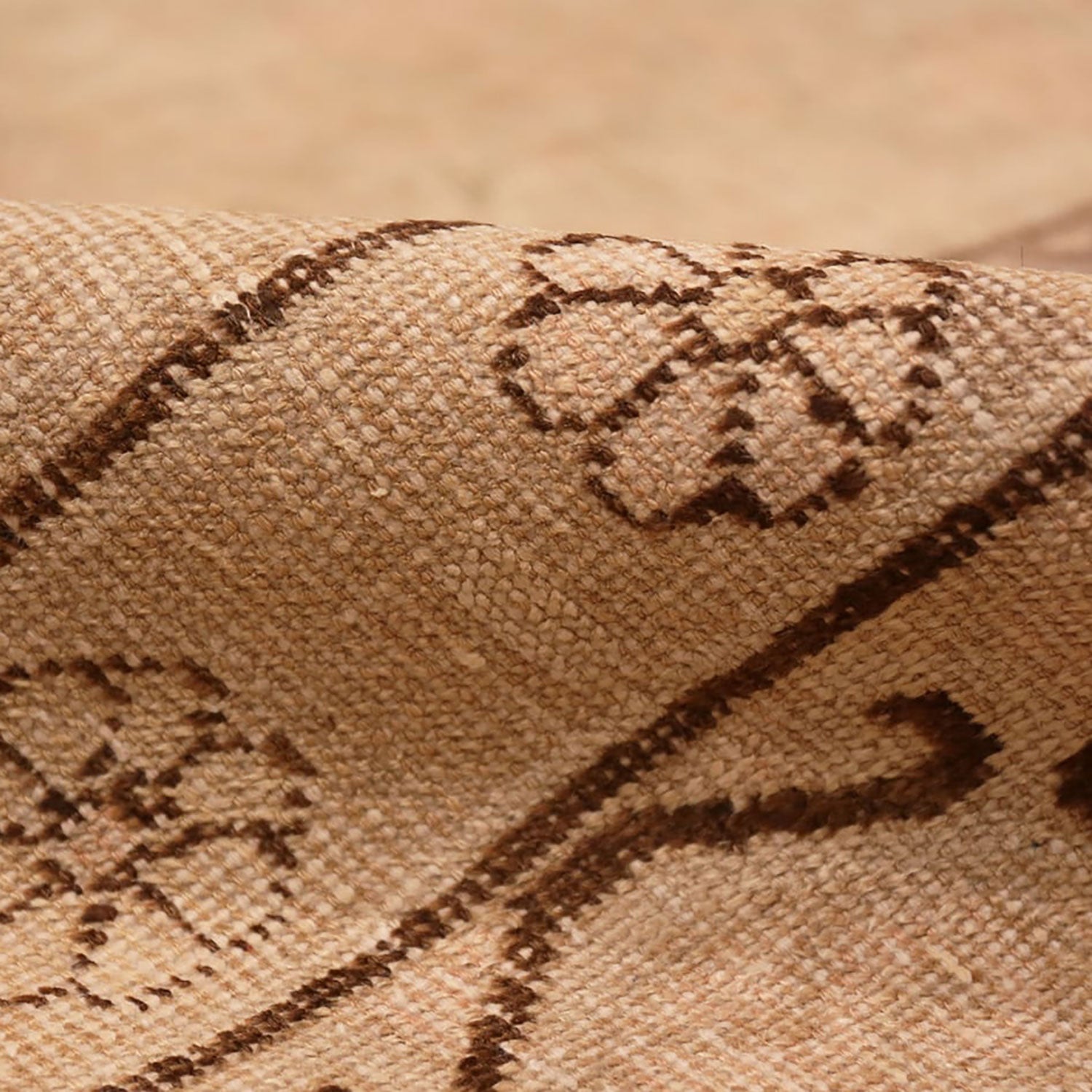 Close-up of a beige fabric with textured weave and brown patterns.