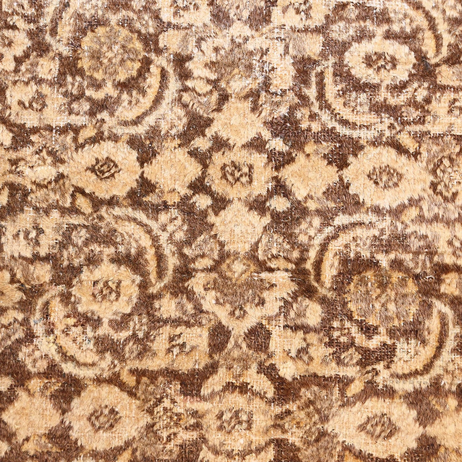 Close-up of a well-used, intricate patterned carpet in warm tones.