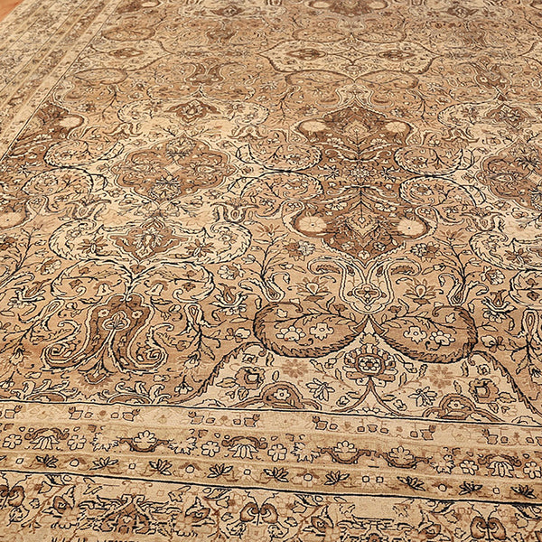 Intricate floral design on handwoven Persian rug in shades of beige and brown.