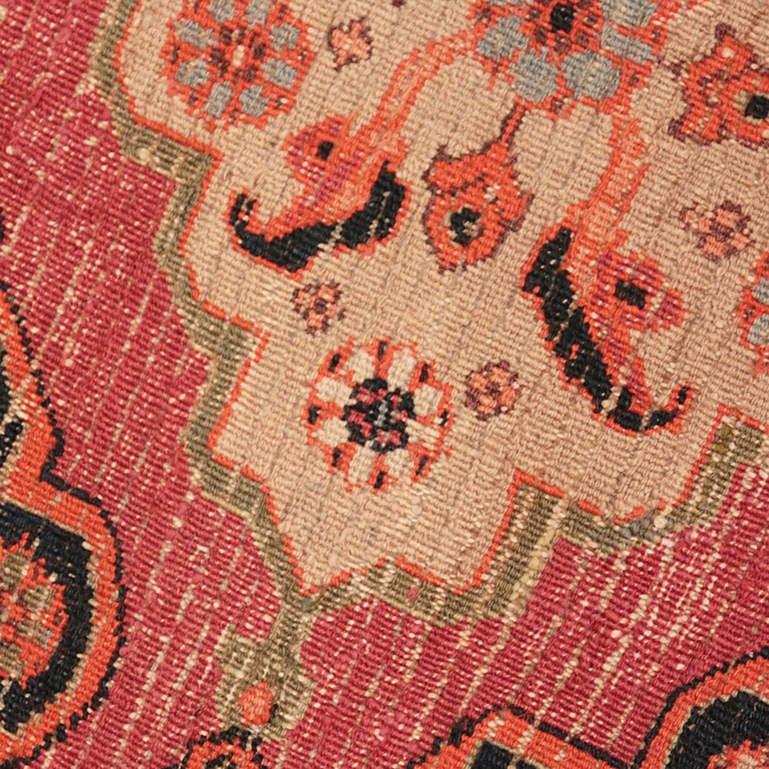Close-up view of a detailed, worn woven rug with floral motif.