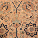 Floral, symmetrical rug with beige, brown, blue hues; handmade, aged.