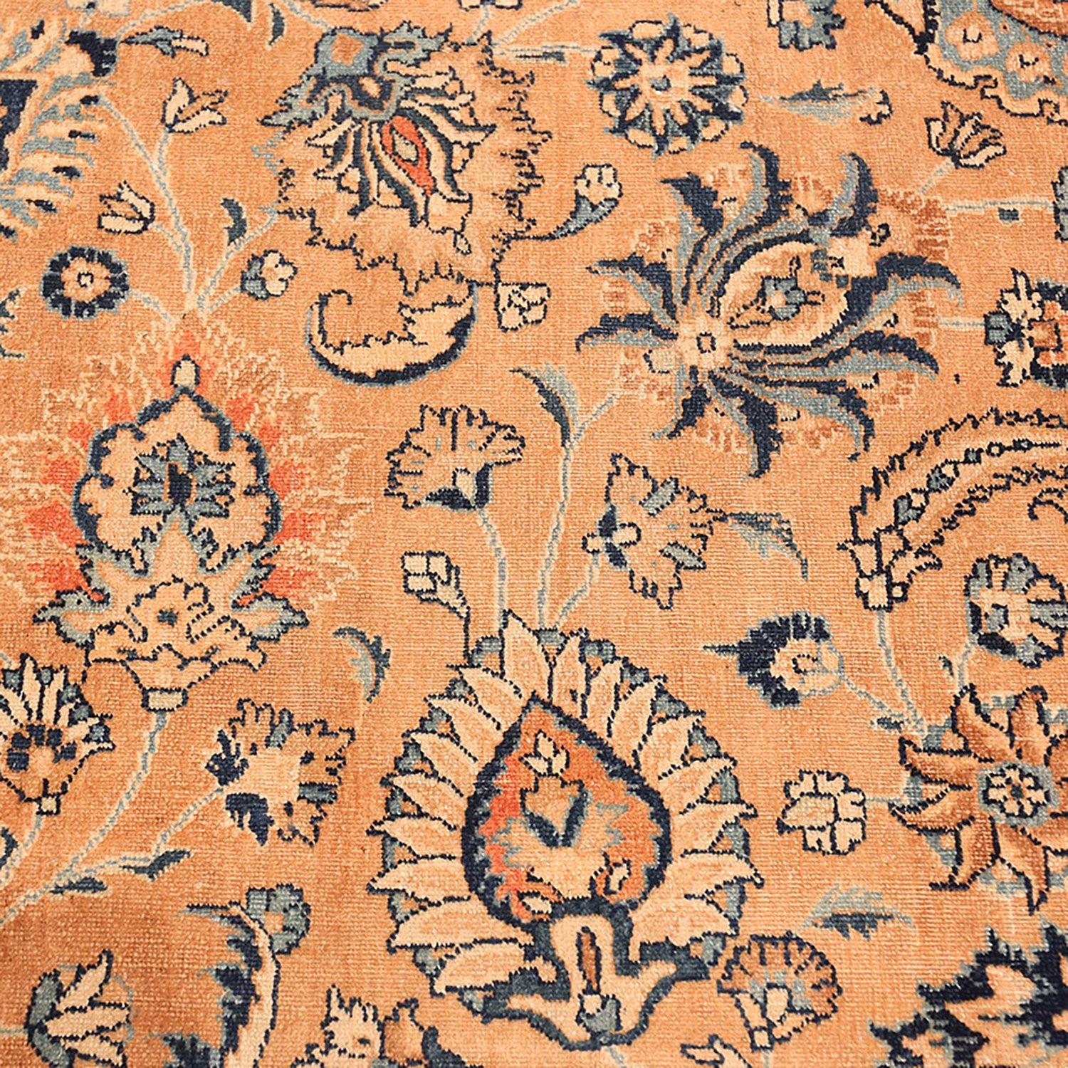 Close-up of worn, antique rug with intricate floral pattern.