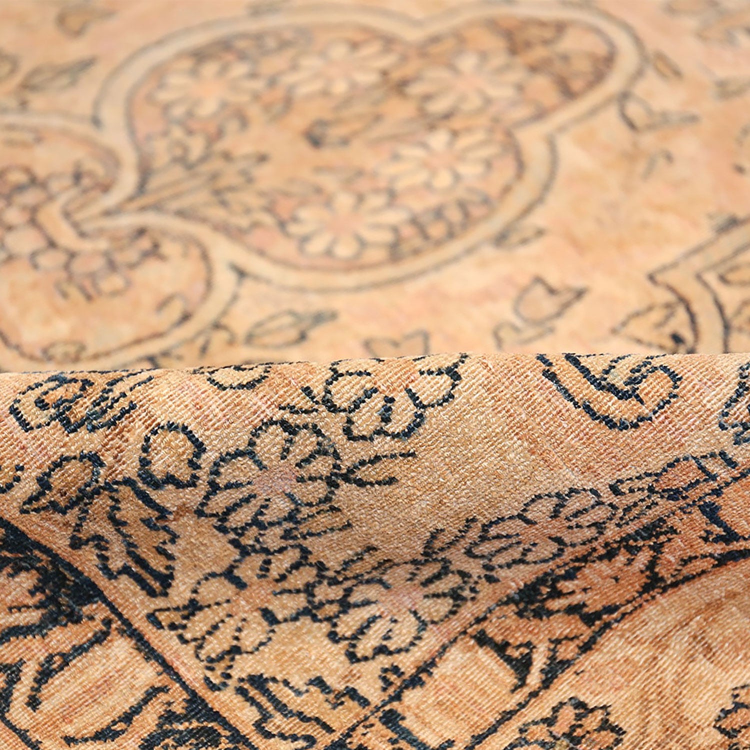 Close-up of a rolled-up patterned carpet with intricate floral design.