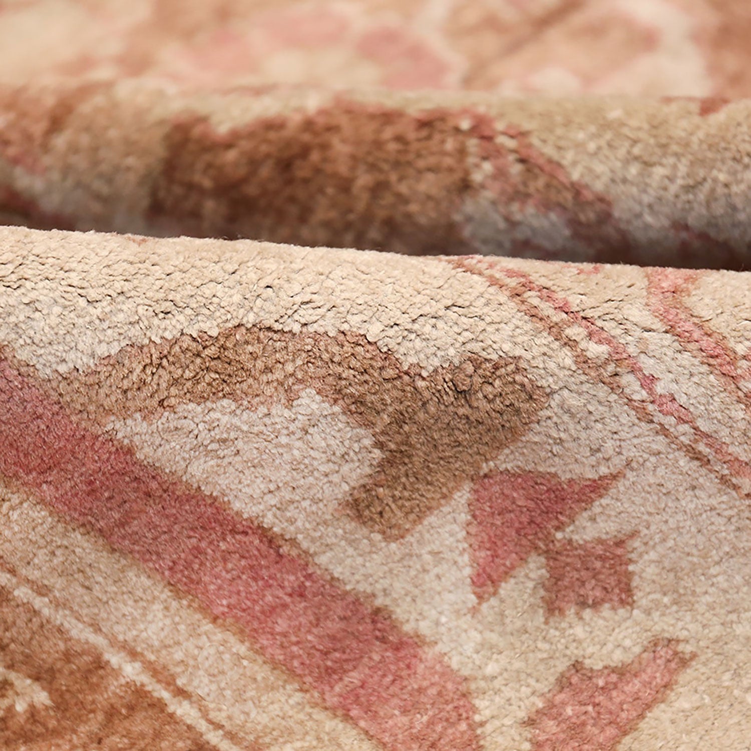 Close-up of a textured, patterned fabric in pink, beige, and brown.