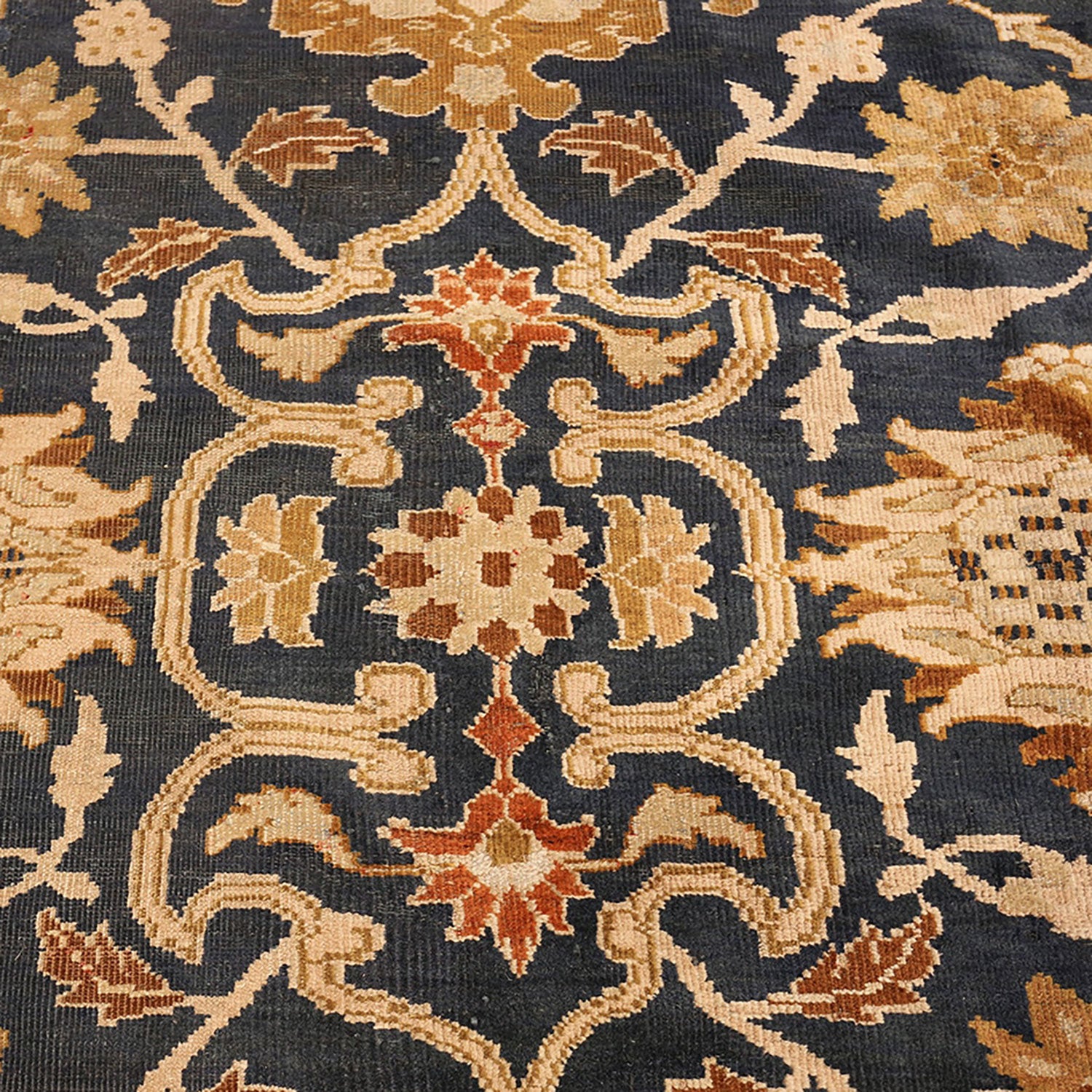 Close-up of an intricate, woven floral-patterned rug in warm tones.