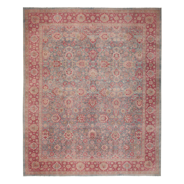 An ornate, vintage-style rug with intricate symmetrical patterns in red and grey tones.