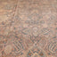 Antique worn-out rug with faded pinkish-tan design and intricate motifs.