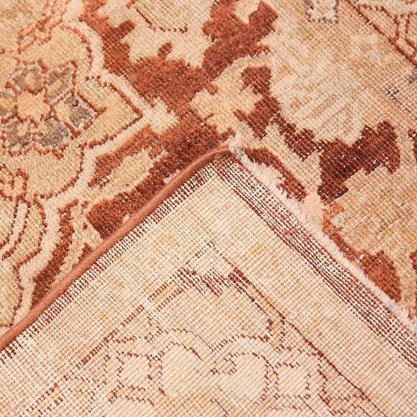 Close-up of ornate patterned carpet with beige and brown hues.