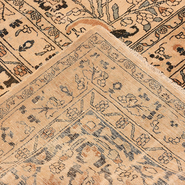 Close-up of vintage rug with intricate floral design in beige.