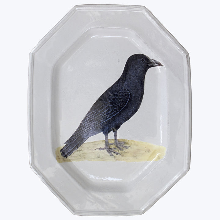 Octagonal glass plate with detailed crow illustration on rim.