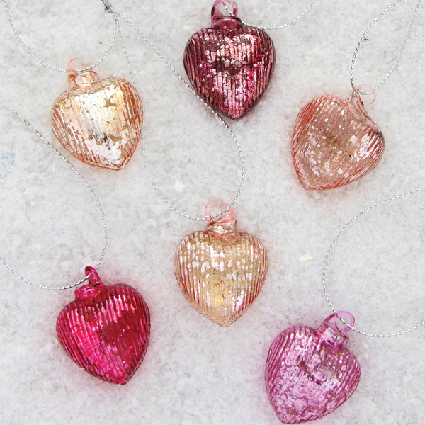 Glittery heart-shaped ornaments on snowy background for festive decorations.