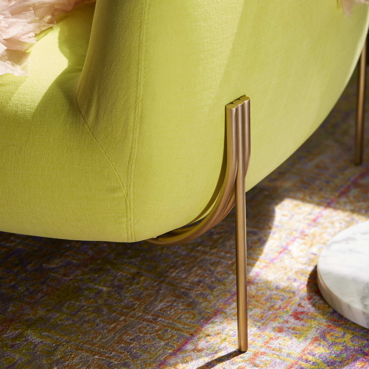 Close-up of a lime green upholstered sofa with metallic leg.