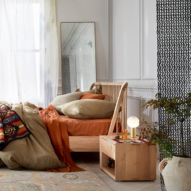 Cozy bedroom featuring burnt orange bedding, chic decor, and natural elements.