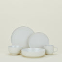Minimalist and modern ceramic dinnerware set against a pale backdrop.