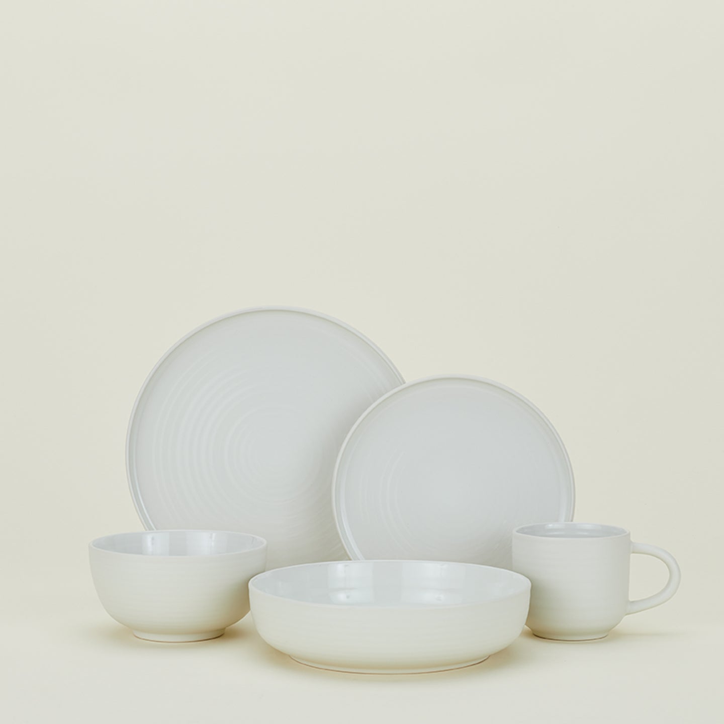 Minimalist and modern ceramic dinnerware set against a pale backdrop.
