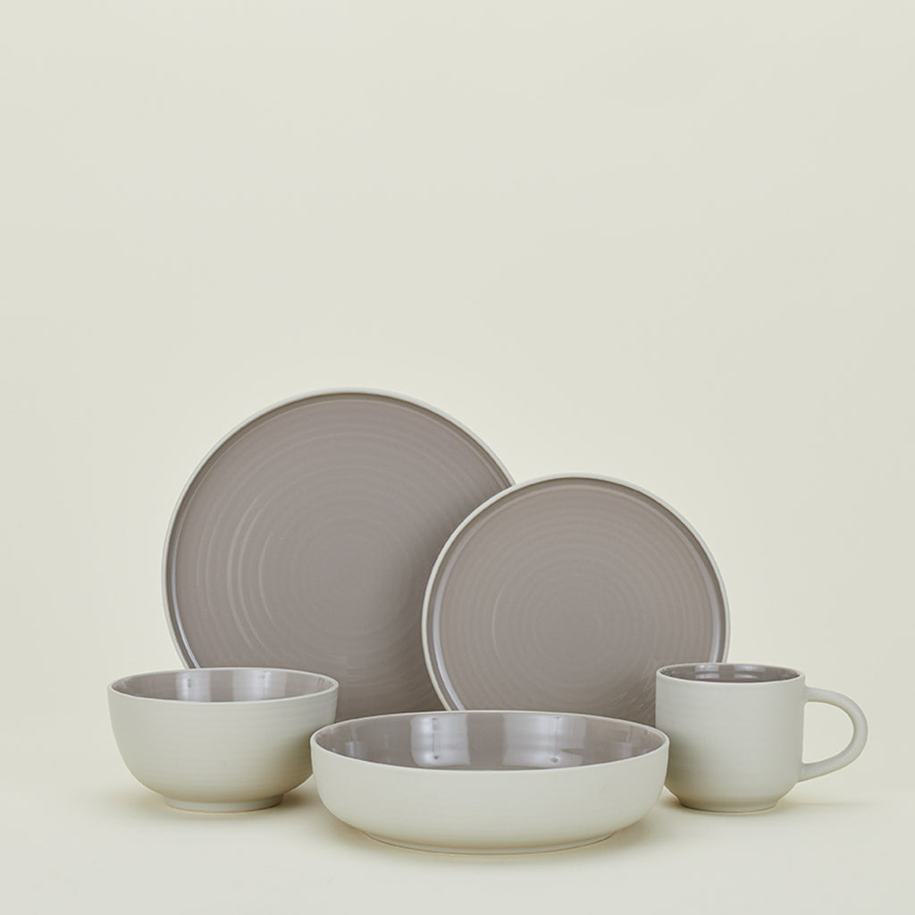 Minimalist ceramic dinnerware set in muted tones against light backdrop.