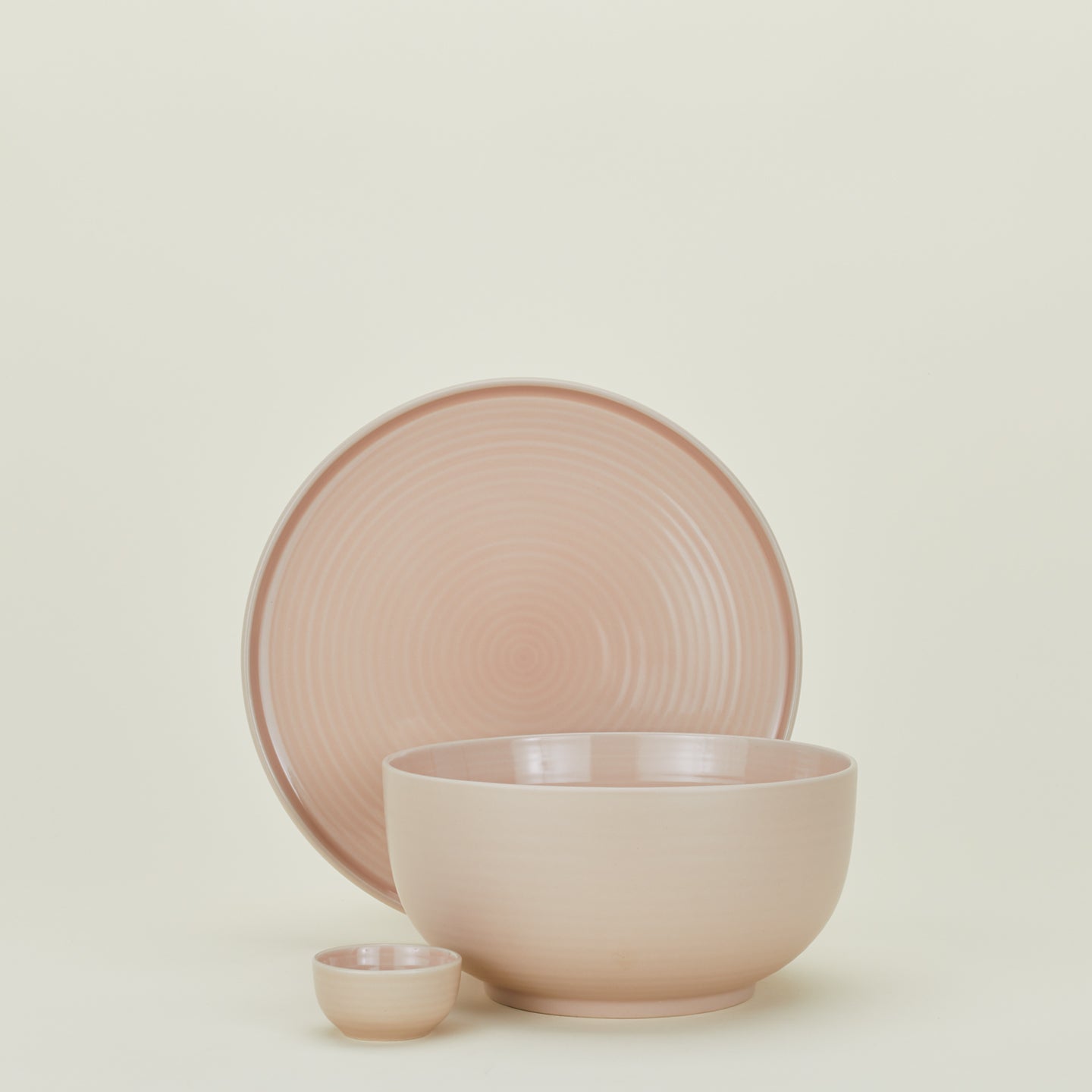 Minimalist ceramic tableware set in pale pinkish beige exudes elegance.