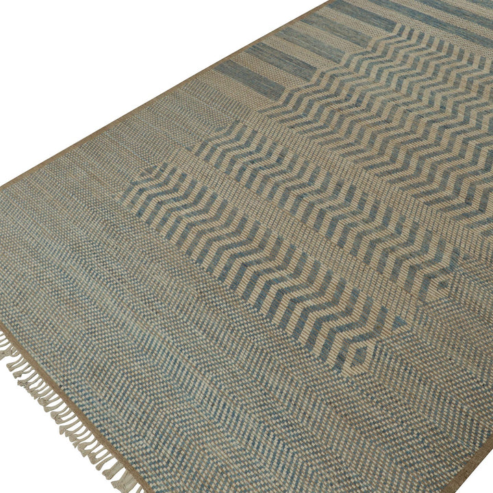 Handwoven blue and beige rug with geometric patterns and fringe.