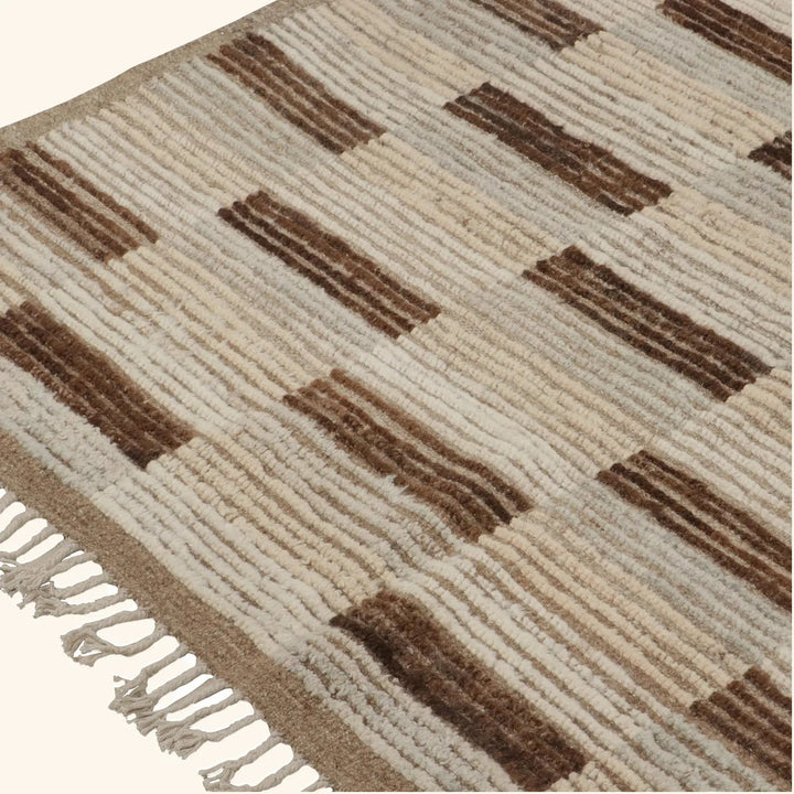 Close-up of textured area rug with brown stripes and fringe