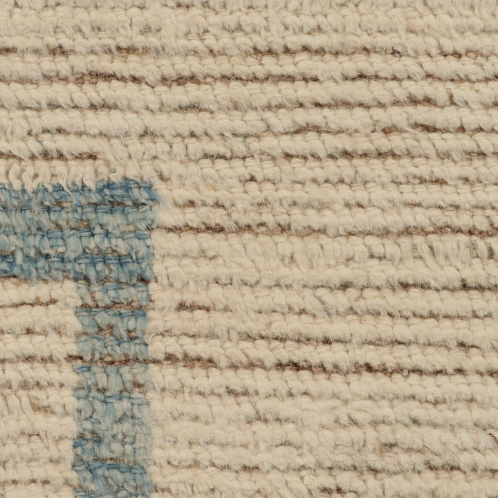 Close-up of textured beige fabric with blue stain, rustic appearance.