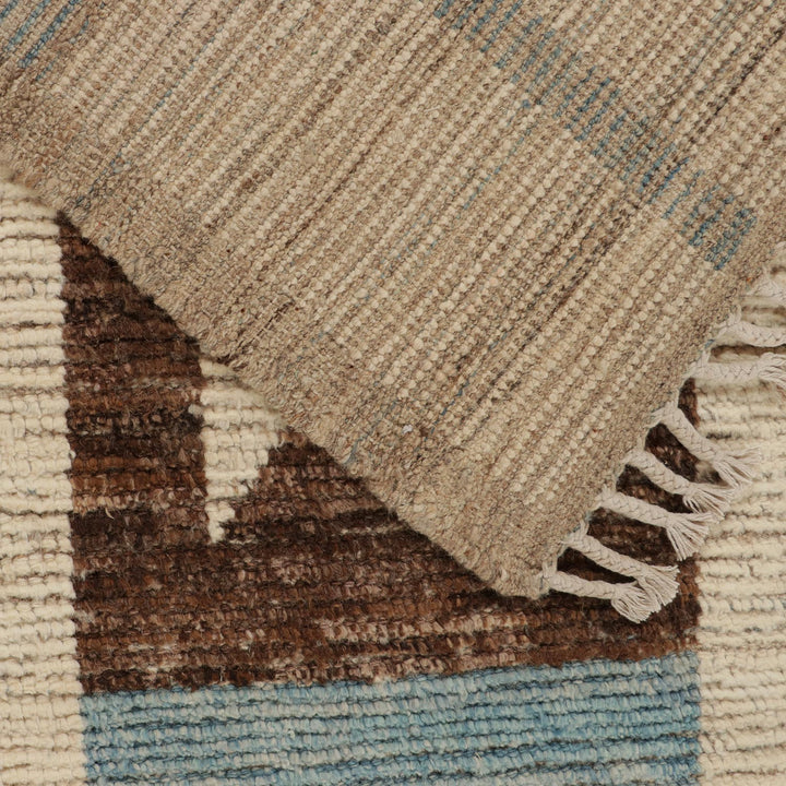 Close-up view of textured woven textile with earthy colors and fringe.