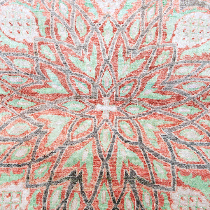 Intricate symmetrical pattern of coral and mint on textured surface.