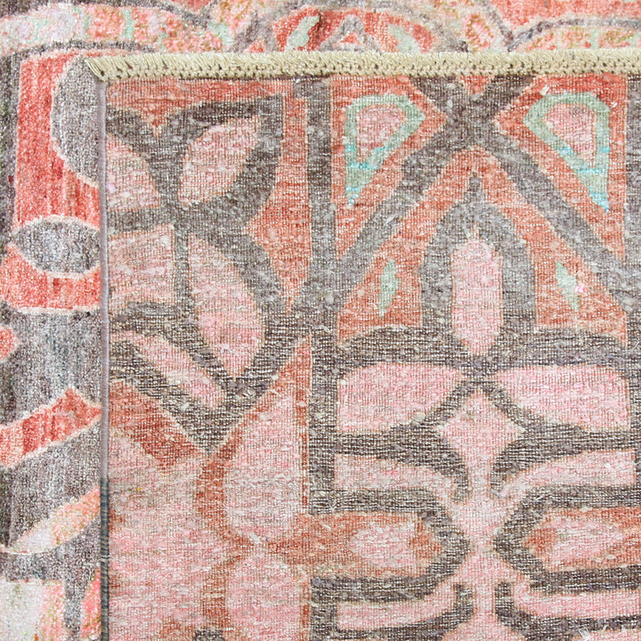 Close-up of textile with geometric and botanical pattern in muted colors.