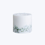 Elegant white candle with green specks and marble pattern design.
