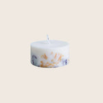 White cylindrical candle with orange and purple marbled design, unlit.