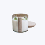 Elegant soy wax candle in glass jar with plant material.