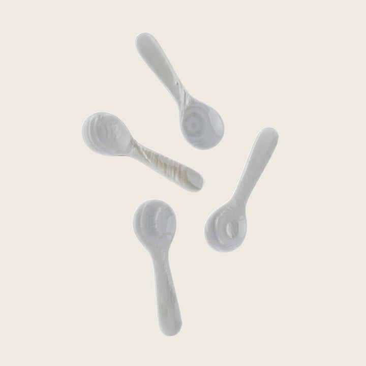 Elegant ceramic spoons arranged on white background with shadows.