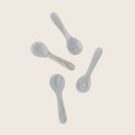 Elegant ceramic spoons arranged on white background with shadows.