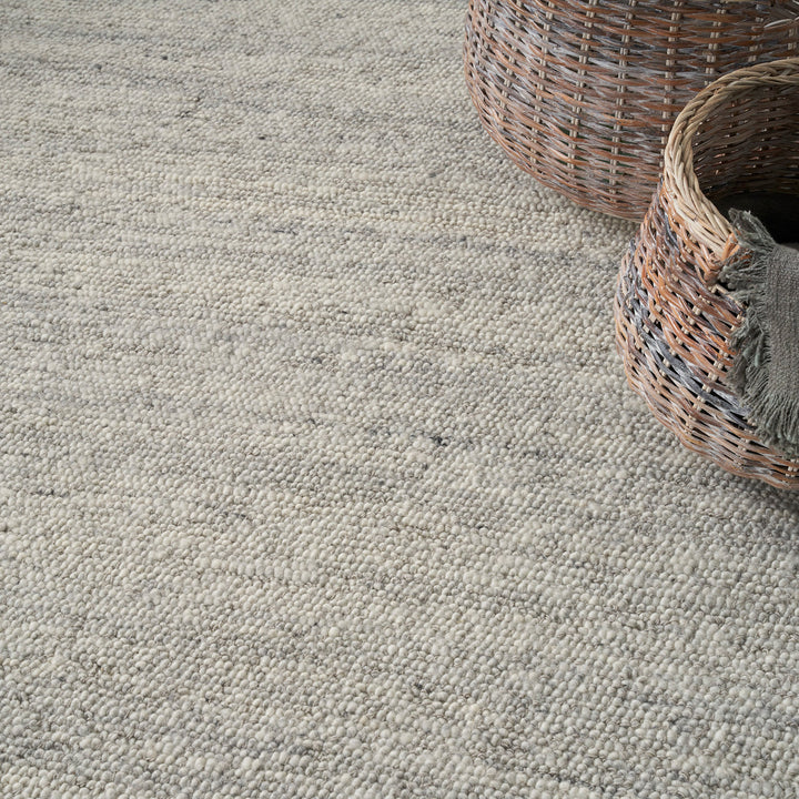 Neutral carpet with woven baskets and blanket exudes cozy decor.