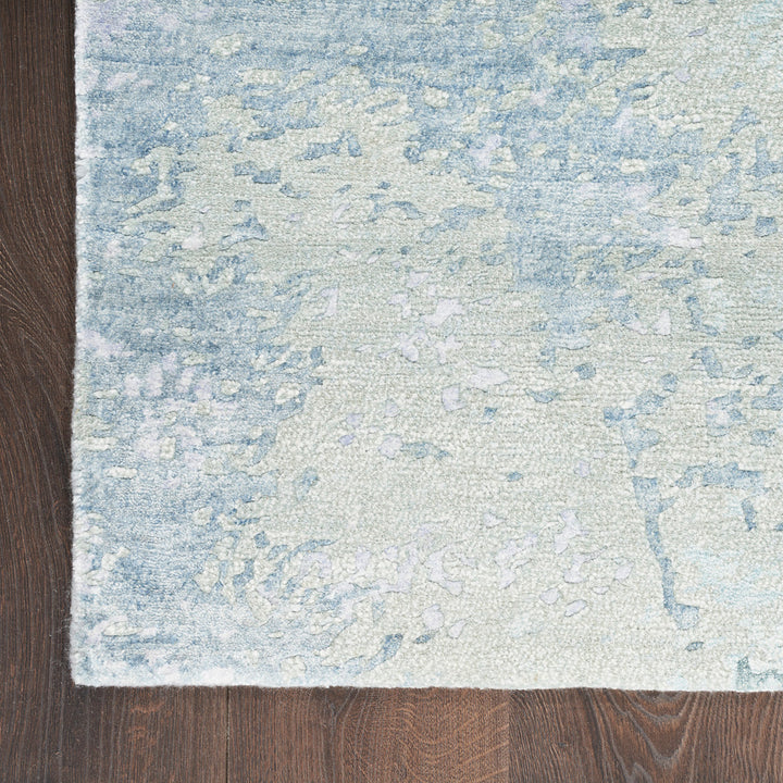 Close-up of distressed blue and off-white area rug on floor.