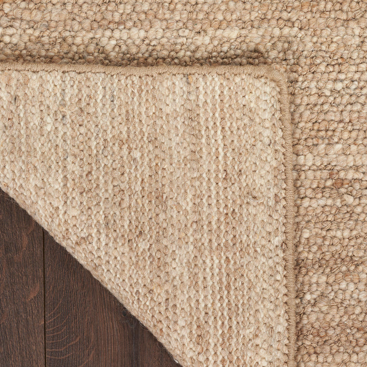 Textured natural fiber rug on wooden floor, robust and rustic.