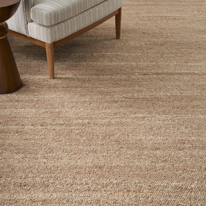 Close-up view of textured beige carpet with mid-century modern sofa.