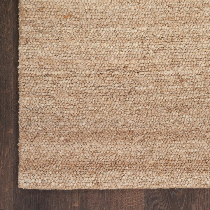 Close-up of beige carpet with looped pile on hardwood floor.