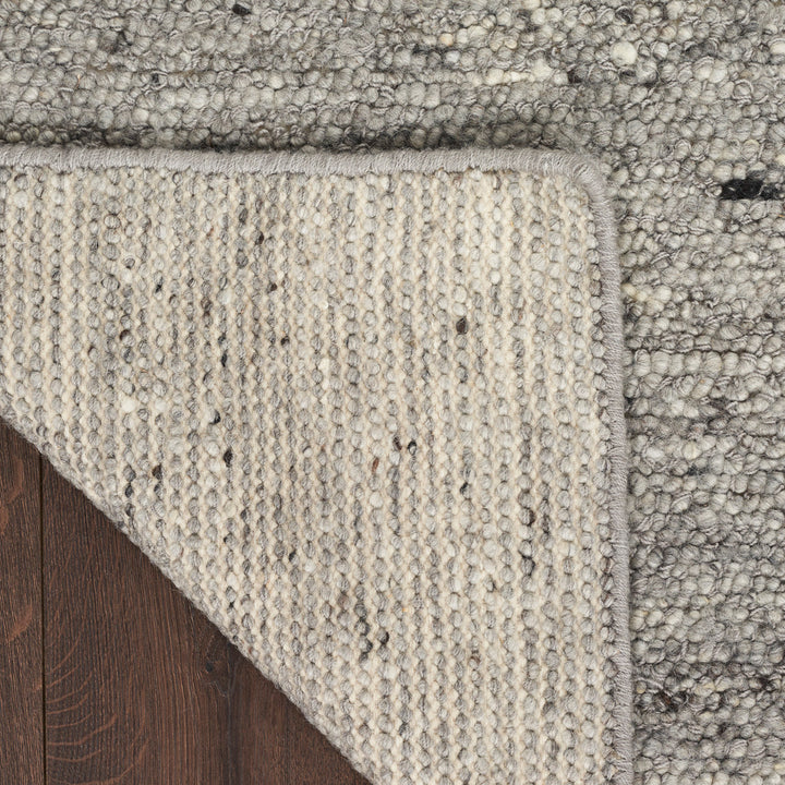 Two layered rugs with textured and looped designs on floor.