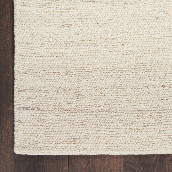 Close-up of cream area rug on dark hardwood floor texture