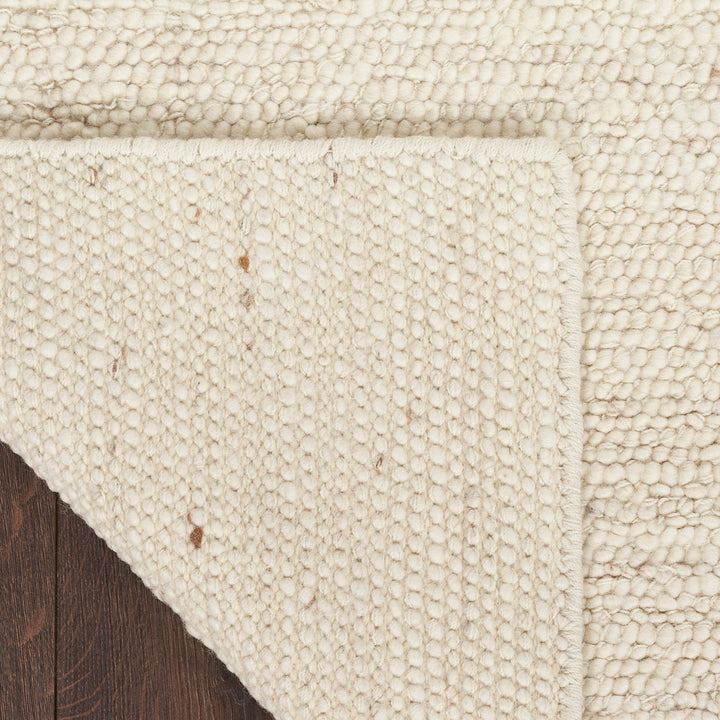 Cozy beige textured blanket with plush pile on hardwood floor.