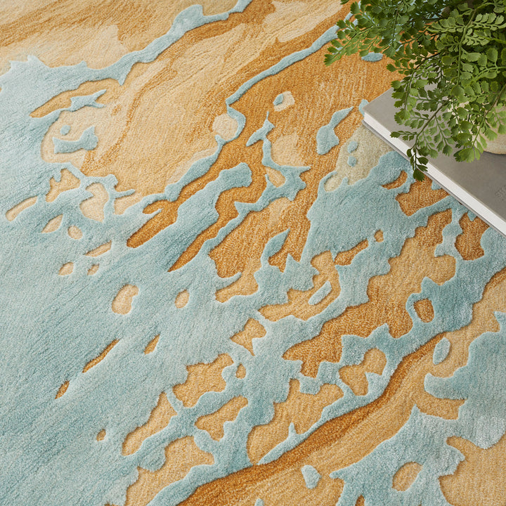 Coastal-themed rug with sandy beach design and green plant.