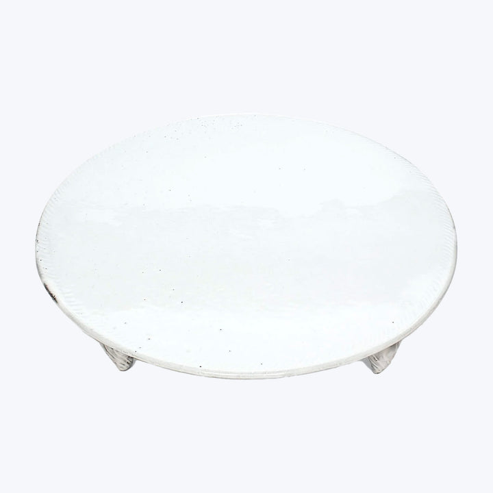 Simple round white ceramic plate with textured surface against white background.