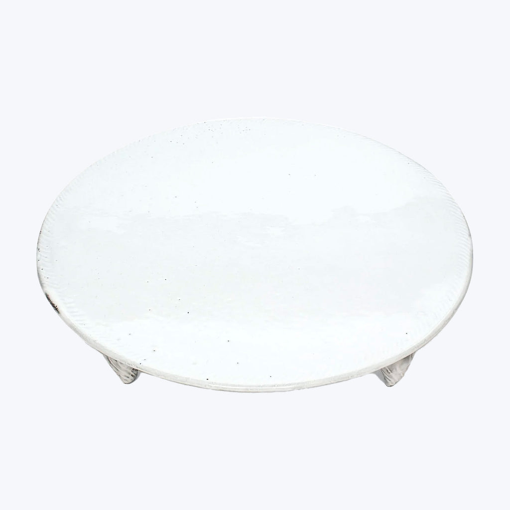 Simple round white ceramic plate with textured surface against white background.