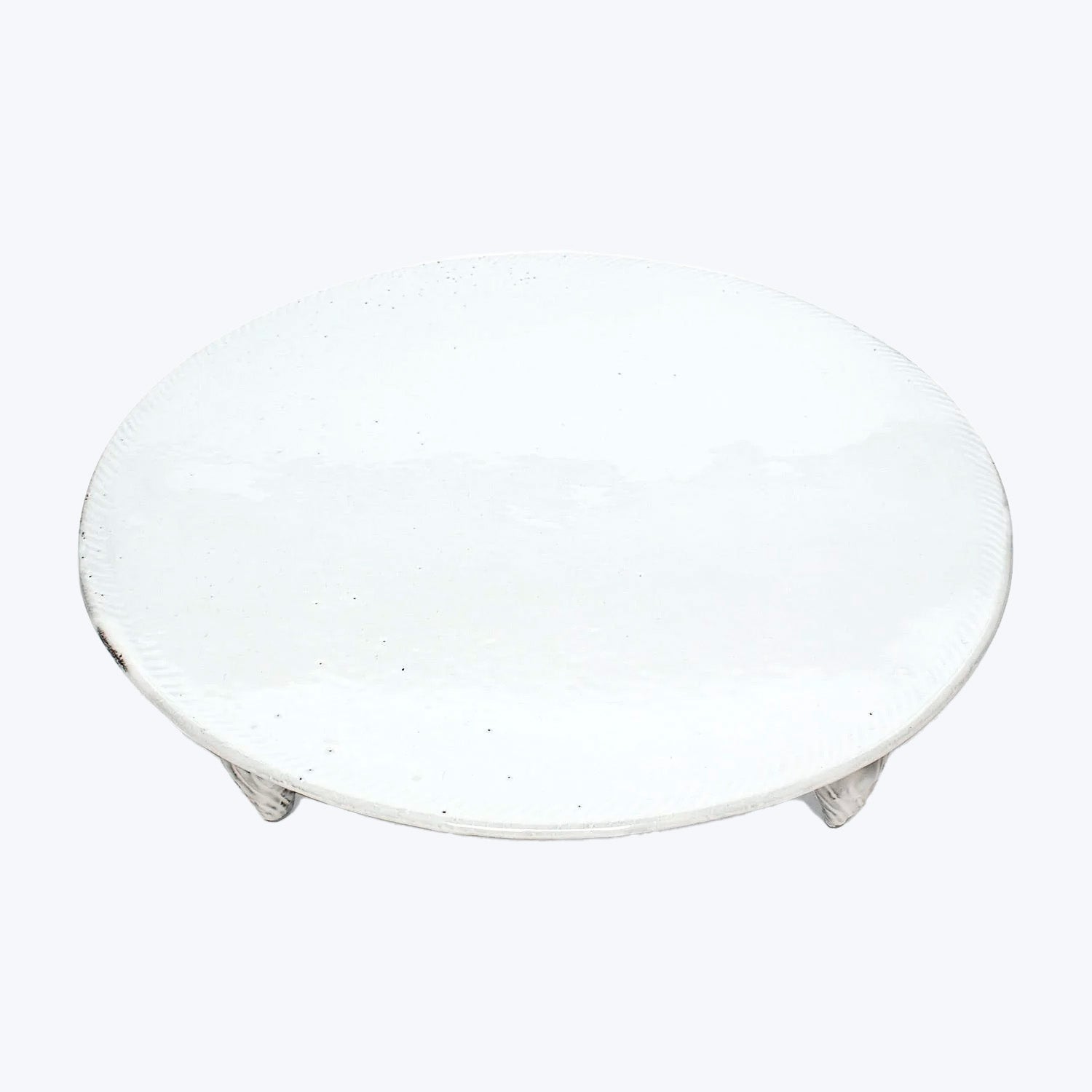 Simple round white ceramic plate with textured surface against white background.