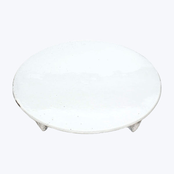 Simple round white ceramic plate with textured surface against white background.